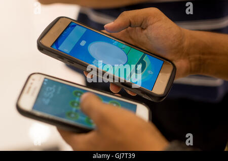 Delhi, India - 24th Jul 2016: man playing pokemon go on multiple phones. people are now outsourcing the playing of this wildly popular game to others Stock Photo