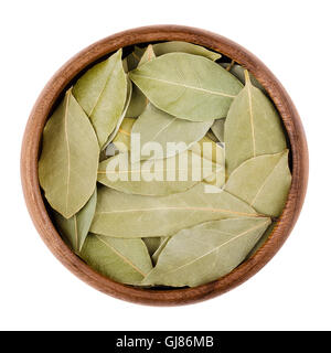 Dried bay leaves in a bowl on white.  Aromatic leaves of Laurus nobilis, also called laurel, used for seasoning in cooking. Stock Photo
