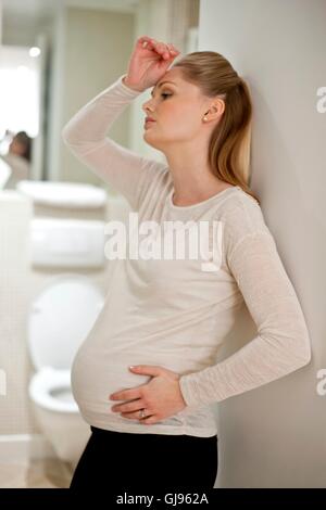 MODEL RELEASED. Pregnant woman with hand on head by bathroom. Stock Photo