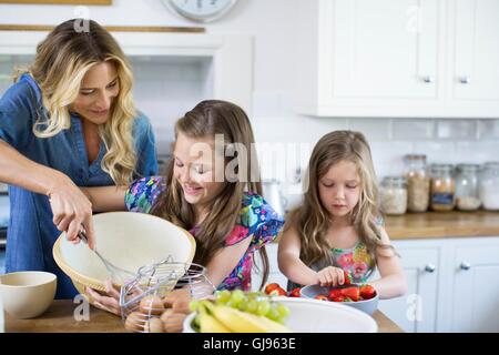 PROPERTY RELEASED. MODEL RELEASED. Mother and two daughters cooking in the kitchen. Stock Photo