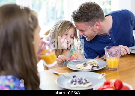 PROPERTY RELEASED. MODEL RELEASED. Father and daughter smiling at breakfast table. Stock Photo