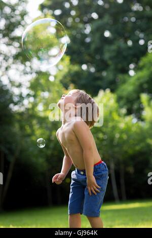 PROPERTY RELEASED. MODEL RELEASED. Boy watching bubble in garden. Stock Photo