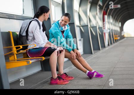 MODEL RELEASED. Two young women sitting on railway platform. Stock Photo