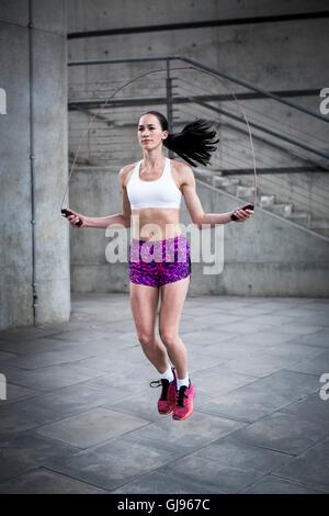 MODEL RELEASED. Young woman skipping with rope. Stock Photo