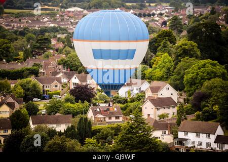 A hot air balloon flies over houses in Long Ashton after taking off in a mass ascent at the Bristol International Balloon Fiesta. Stock Photo