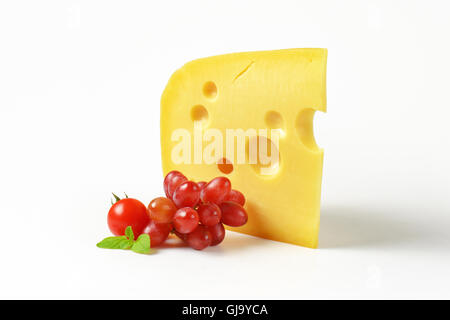 wedge of fresh cheese with red grapes on white background Stock Photo