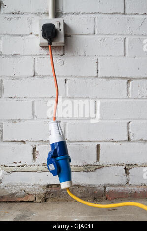 Caravan electrical hook-up cable with mains power adapter plugged into 240V mains socket, England, UK Stock Photo