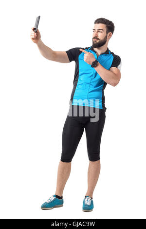 Side view of cyclist in blue jersey t-shirt taking selfie and pointing finger at camera. Full body length portrait on white Stock Photo