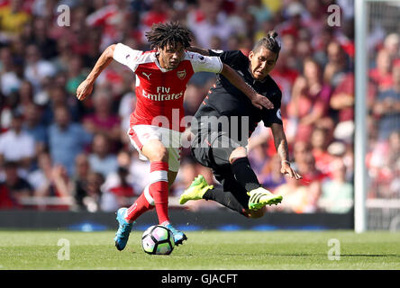 Arsenal's Mohamed Elneny (left) and Liverpool's Roberto Firmino battle for the ball during the Premier League match at the Emirates Stadium, London. Stock Photo