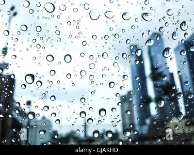Rain drops cling to a car window glass with skycrapers on the background Stock Photo