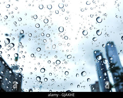 Rain drops cling to a car window glass with skycrapers on the background Stock Photo