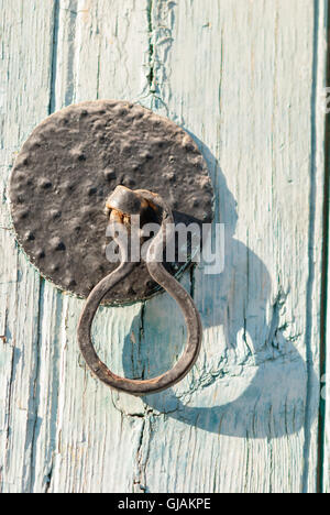 Old rusted black door knocker on a shabby blue door closeup. Kato Drys. Cyprus. Stock Photo
