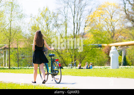 Young woman wearing black short dress riding bike Stock Photo