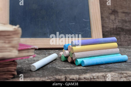 chalks and old school books on wooden  desk  with slate background Stock Photo