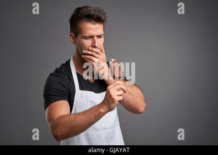 A handsome young barista man having a toothache while eating an ice-cream Stock Photo