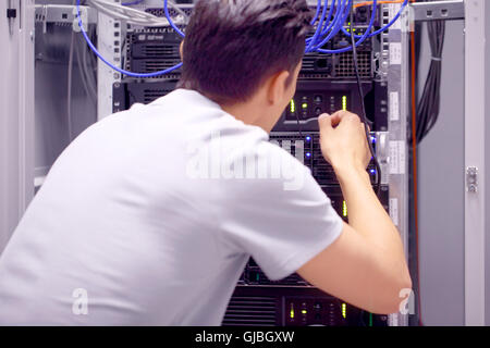 Young engeneer man in network server room connecting wires Stock Photo