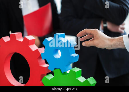 Business people assembling cogwheels, teamwork concept Stock Photo