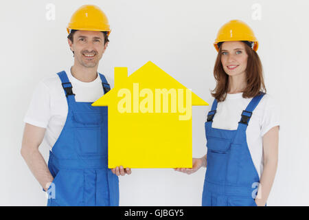 Happy smiling workers in hardhats holding house model Stock Photo