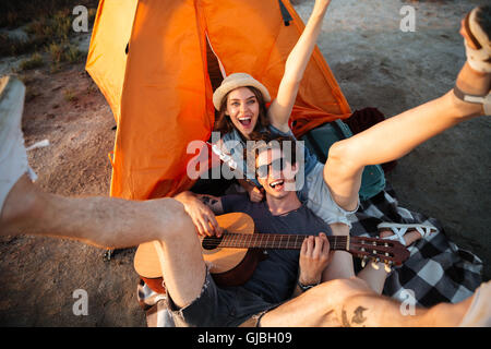 Happy young cheerful couple having fun camping by a lake Stock Photo