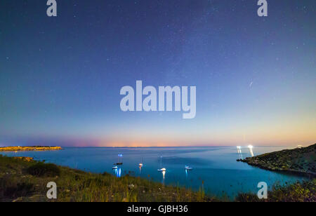 Long exposure of Mgiebah Bay in Malta on a clear summer night.  Street lights from Sicily can be clearly seen in the background Stock Photo