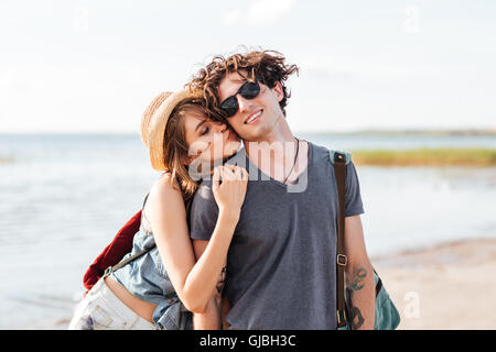 Beautiful young couple with backpacks standing and kissing on the beach Stock Photo
