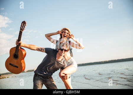 Portrait of a happy young couple having fun on the beach, posing and showing v sign Stock Photo