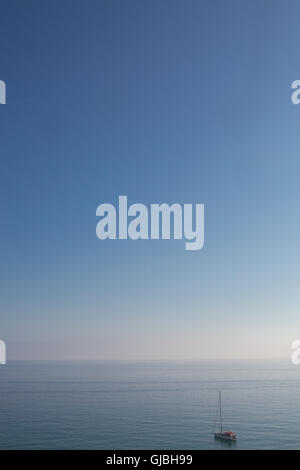 A lone yacht in a vast blue backdrop of sea and sky Stock Photo