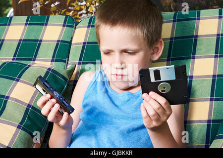 Little boy with floppy disk and audio cassette outdoors Stock Photo