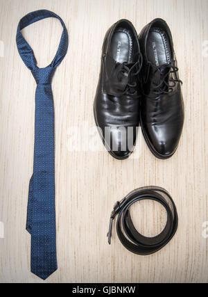 Set of men's clothing and shoes on wooden background. Men accessories. Black elegant pieces isolated white table. Stock Photo
