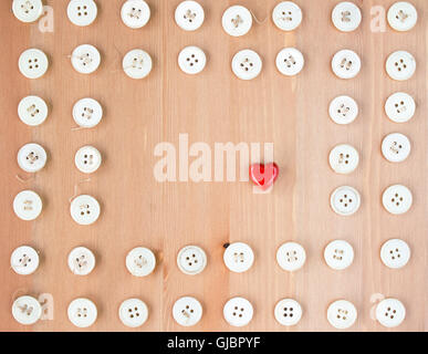 Old vintage buttons frame border with red wooden hearts in the middle. Sewing, hobby, lifestyle concept Stock Photo