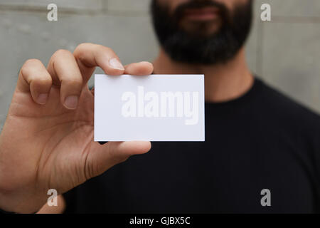 Bearded Man Wearing Casual Black Tshirt Showing Blank White Business Card.Blurred Background Ready Corporate Private Information.Horizontal Mockup. Stock Photo