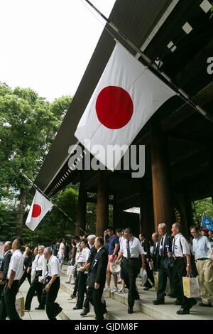 Tokyo, Japan. 15th Aug, 2016. People walk under Japanese flags flying at half-mast out of respect for the war dead at the entrance of Yasukuni Shrine on the 71st anniversary of Japan's surrender in World War II on August 15, 2016, Tokyo, Japan. Some 70 lawmakers visited the Shrine to pay their respects, but the Prime Minister Shinzo Abe did not visit the controversial symbol and instead sent a ritual offering to a shrine. Credit:  Aflo Co. Ltd./Alamy Live News Stock Photo