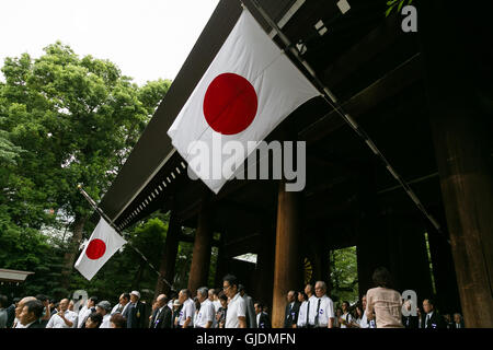 Tokyo, Japan. 15th Aug, 2016. People walk under Japanese flags flying at half-mast out of respect for the war dead at the entrance of Yasukuni Shrine on the 71st anniversary of Japan's surrender in World War II on August 15, 2016, Tokyo, Japan. Some 70 lawmakers visited the Shrine to pay their respects, but the Prime Minister Shinzo Abe did not visit the controversial symbol and instead sent a ritual offering to a shrine. Credit:  Aflo Co. Ltd./Alamy Live News Stock Photo
