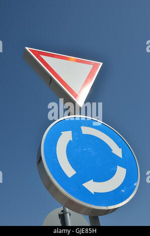 roundabout and give way sign on blue sky Stock Photo