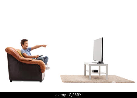Laughing child seated on an armchair watching something hilarious on tv isolated on white background Stock Photo