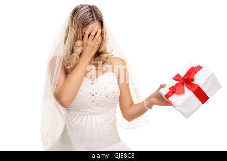 Young disappointed bride holding a wedding present in her hand isolated on white background Stock Photo