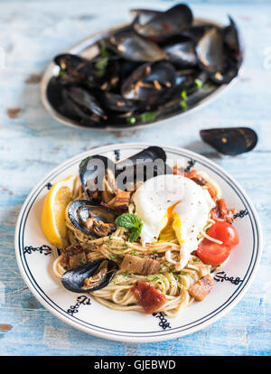 Served plate mussel with spaghetti and boiled egg on wooden background,selective focus Stock Photo