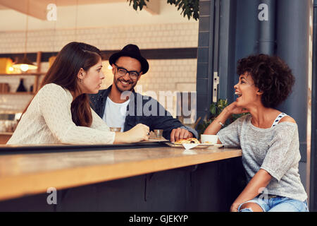 Portrait of a young group of friends talking in a cafe. Young man and women sitting at cafe table and talking. Stock Photo
