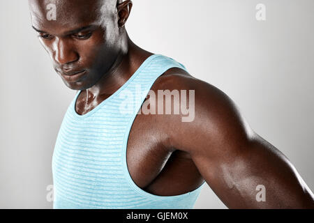 Close up shot of muscular young african man looking down over grey background. Stock Photo