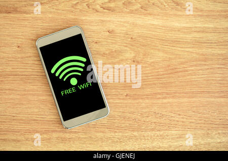 Free Wifi Available. Smart phone on wood background with free Wifi sign. Stock Photo