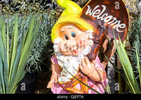 Hilarious funny, smiling dwarf with a white beard, digs earth and invites in your garden Stock Photo