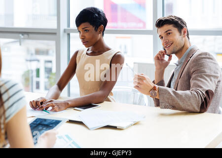 Group of smiling young businesspeople preparing for presentation in office Stock Photo