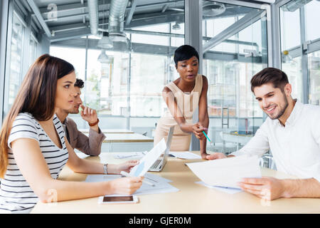 Group of enthusiastic cheerful colleagues discussing ideas and planning work in office Stock Photo