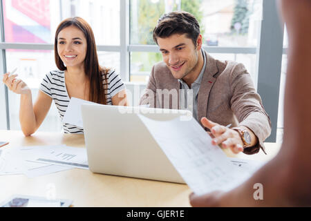 Smiling woman and man working and discussing project and using laptop in the office Stock Photo