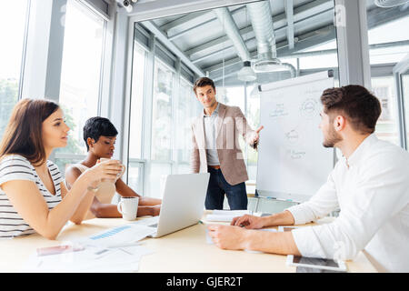 Successful young businessman making presentation of business plan using flipchart in office Stock Photo