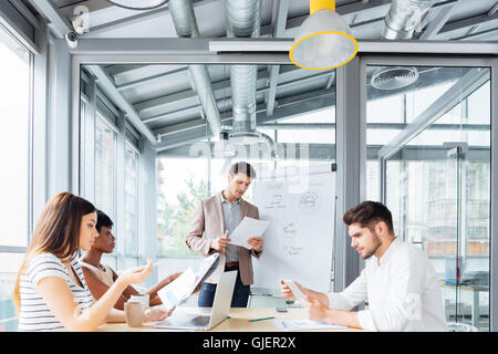 Concentrated young businessman giving presentation and reading documents in office Stock Photo