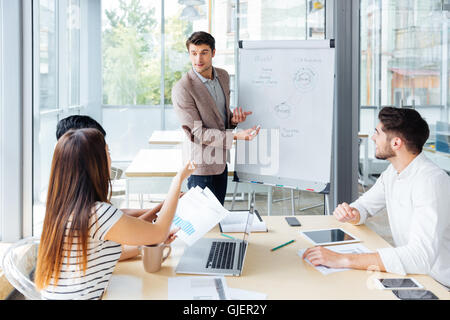 Confident handsome young businessman giving presentation using flipchart in office Stock Photo