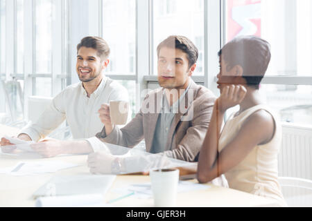 Group of cheerful young business people sitting and listening presentation in office Stock Photo