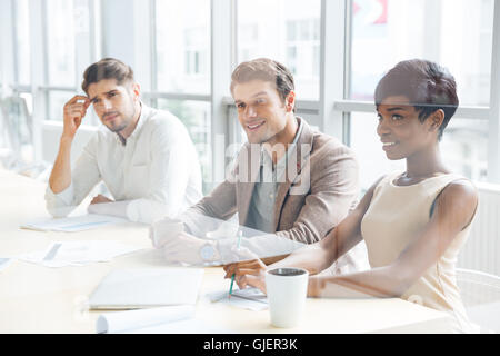 Smiling young business people sitting on training and making notes in office Stock Photo
