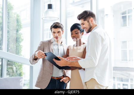 Three young business people standing and discussing business plan together in office Stock Photo